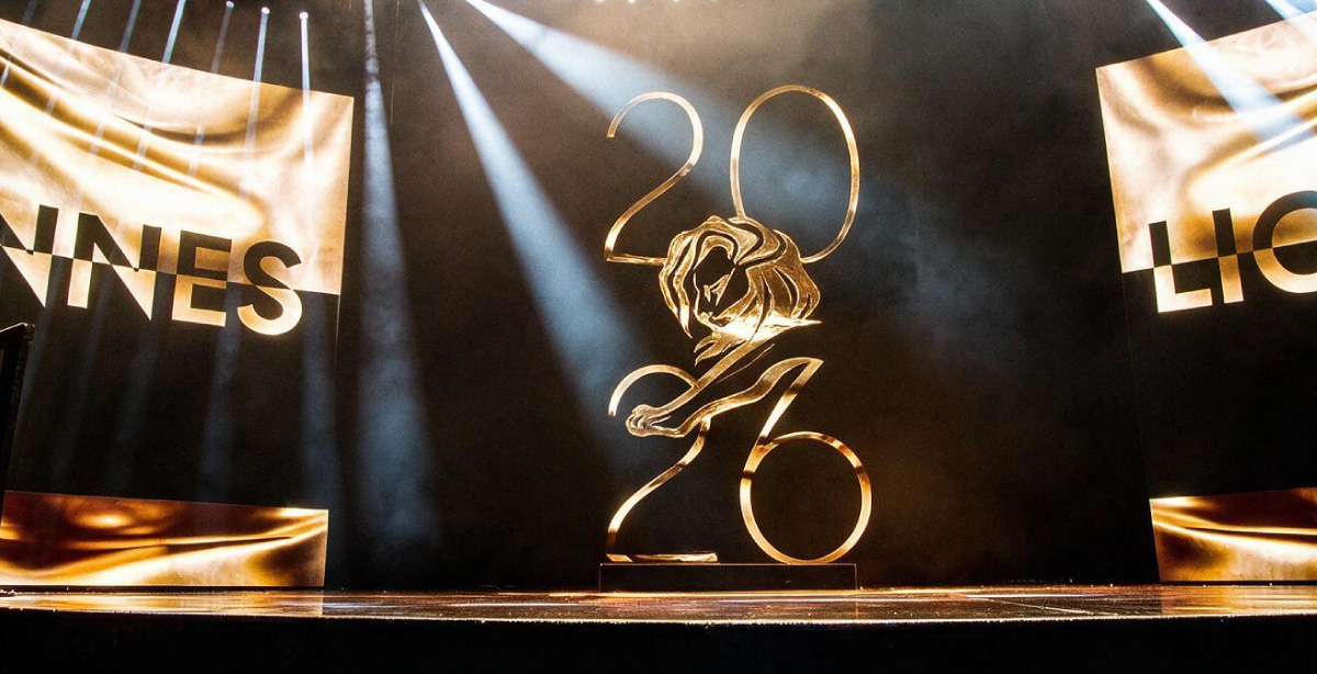 Palco iluminado com a escultura dourada do Cannes Lions 2026 ao centro, destacando o número do ano e o leão símbolo do festival.